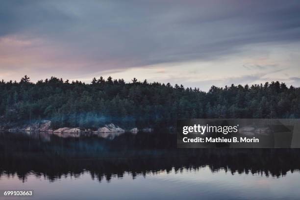 calm lake at dusk with a canoe crossing over - ヒューロン湖 ストックフォトと画像