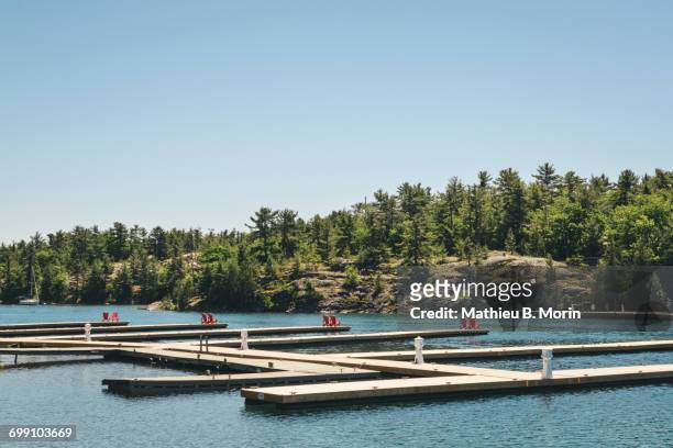 red adirondack chairs placed at each end of a wharf for the locals and tourists in the municipality of killarney, ontario - killarney canada stockfoto's en -beelden