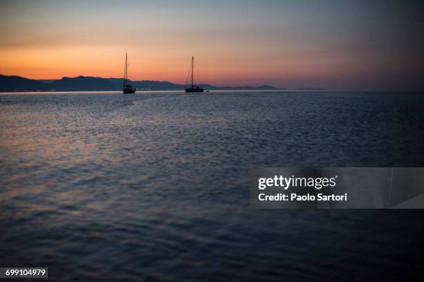 sailboats at sunrise in cala goloritz. sardinia, italy. - cala goloritze stock-fotos und bilder