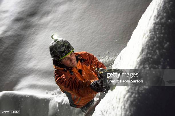 man ice climbing in urban environment by night in simplonpass, switzerland. - eisklettern stock-fotos und bilder