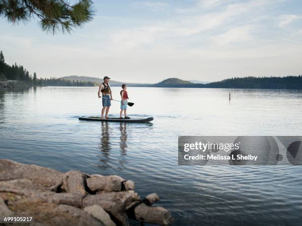 father and son paddle an sup on calm waters - paddleboarding ストックフォトと画像