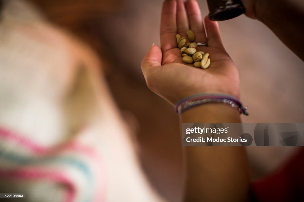 A young woman tests coffee beans while they are being roasted at a coffee facility in rural Colombia.