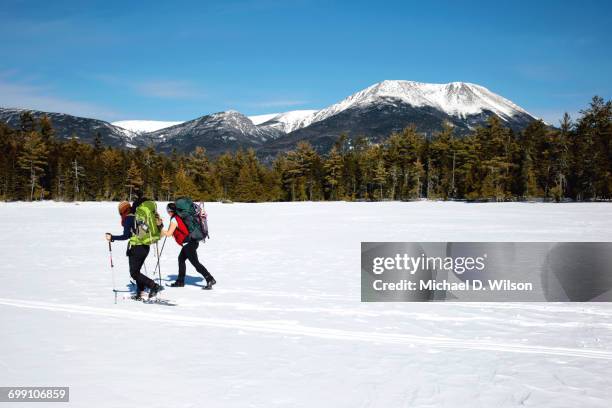 snowshoers crossing a frozen pond in baxter state park. - baxter state park stock pictures, royalty-free photos & images