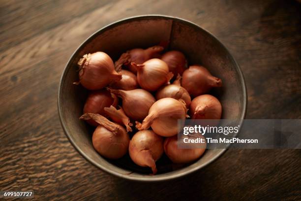 overhead view of fresh whole shallots in bowl - halstock stock-fotos und bilder