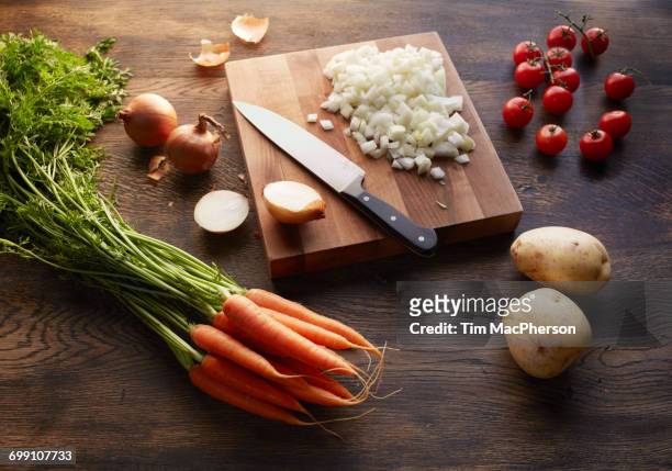 "fresh carrots, potatoes and cherry tomatoes with onions chopped on cutting board" - halstock stock-fotos und bilder