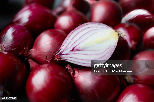 fresh whole red onions and one halved on table - halstock stock pictures, royalty-free photos & images