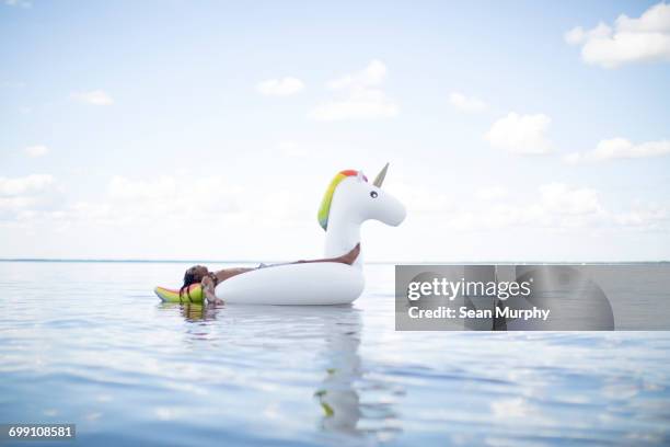 "young man lying back on inflatable unicorn in sea, santa rosa beach, florida, usa" - the tanning of america stock pictures, royalty-free photos & images