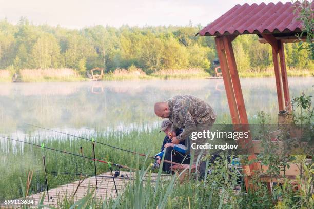 the father trains the son to catch fish on the river bank. - head mount display stock pictures, royalty-free photos & images