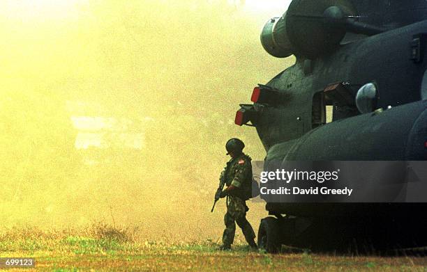Special forces soldier stands guard in the downdraft of a NH-47D Chinook helicopter February 17, 2002 at the 103rd Brigade camp on the southern...