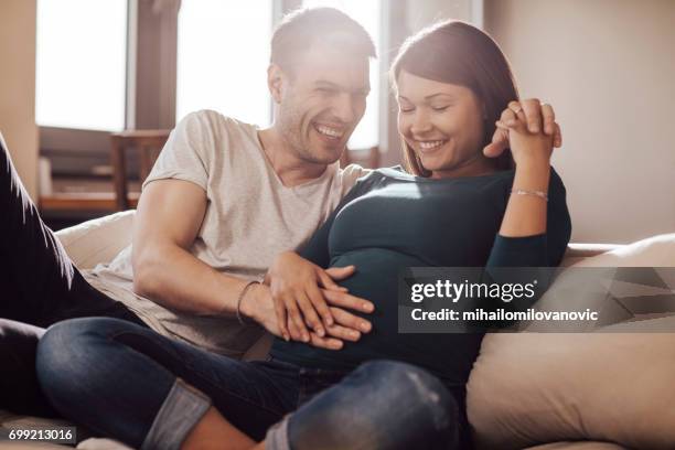 husband touching wife's stomach - pregnant home stock pictures, royalty-free photos & images