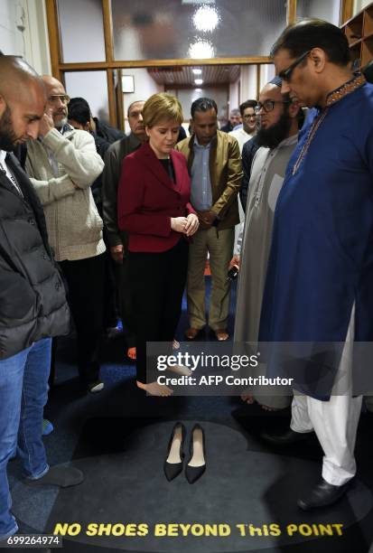 Scotland's First Minister and Scottish National Party leader Nicola Sturgeon puts her shoes on after meeting worshippers during a visit to Dundee...