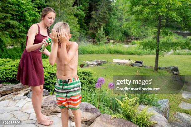 teenager spraying insect repellant on boy in summer nature. - preteen girl no shirt stock pictures, royalty-free photos & images