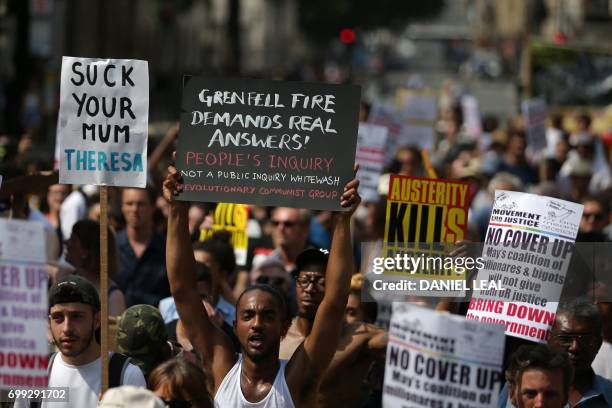 Demonstrators hold up placards as they march through central London on June 21, 2017 en route to Parliament, during an anti-government protest to...