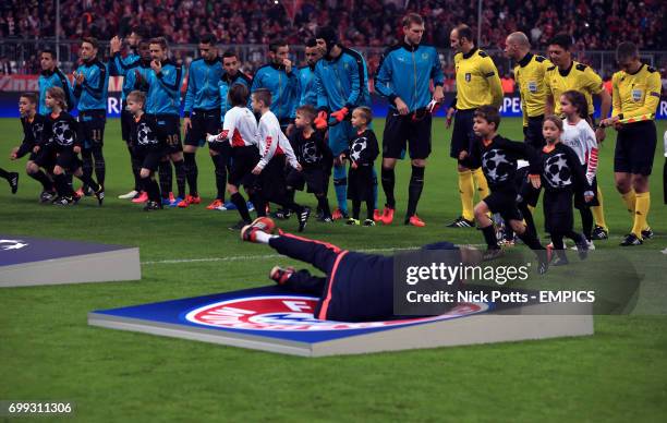 Member of staff falls over the Bayern Munich giant crest on the pitch before the game as the players line up for the anthems