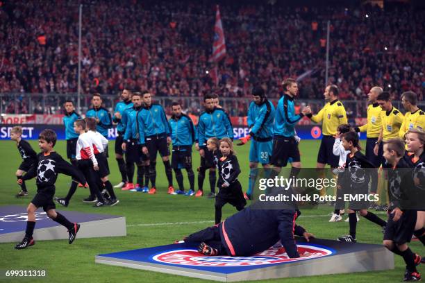 Member of staff falls over the Bayern Munich giant crest on the pitch before the game as the players line up for the anthems