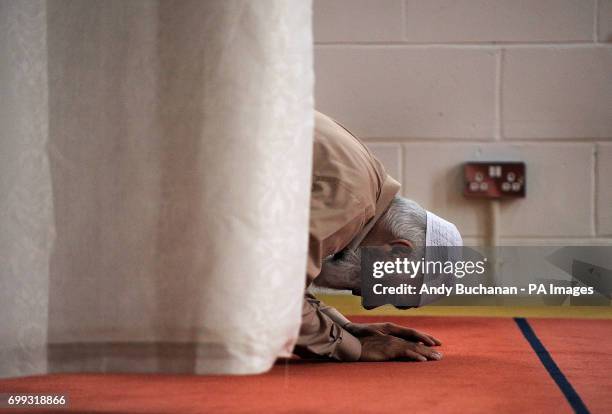 Men kneel and pray as Scotland's First Minister Nicola Sturgeon meets worshippers during a visit to Dundee Central Mosque in Dundee.