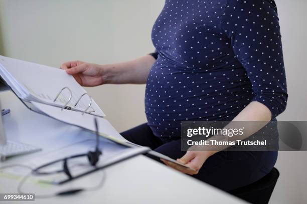 Berlin, Germany Posed scene: A pregnant woman is sitting at a desk in the office on June 21, 2017 in Berlin, Germany.