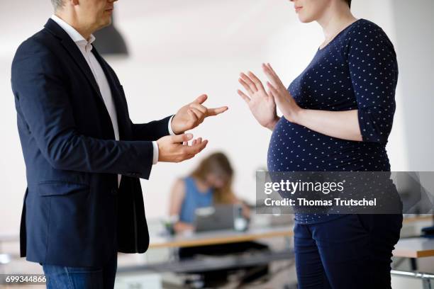 Berlin, Germany Posed scene: A pregnant woman and a supervisor gesture in the office on June 21, 2017 in Berlin, Germany.