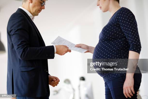 Berlin, Germany Posed scene: A pregnant woman hands a paper to a supervisor in the office on June 21, 2017 in Berlin, Germany.