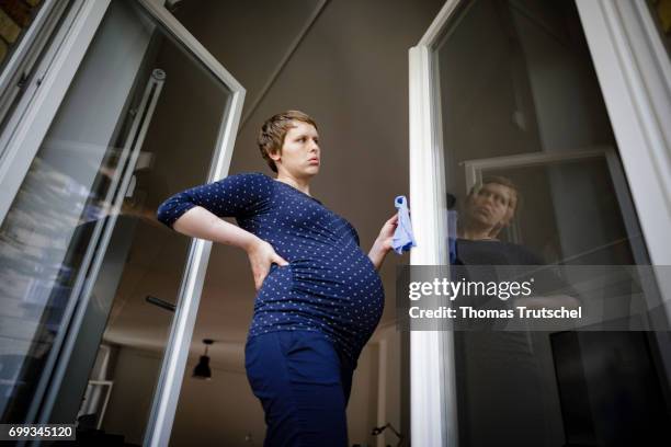 Berlin, Germany Posed scene: A pregnant woman is holding her painful back while she is cleaning windows on June 21, 2017 in Berlin, Germany.