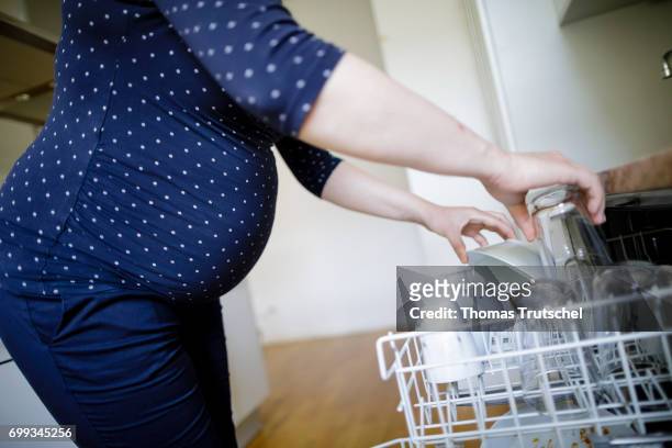 Berlin, Germany Posed scene: A pregnant woman is filling the dishwasher on June 21, 2017 in Berlin, Germany.
