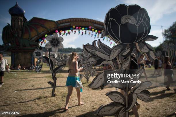 People pass wooden flowers as temperatures reach record levels at the Glastonbury Festival at Worthy Farm in Pilton on June 21, 2017 near...