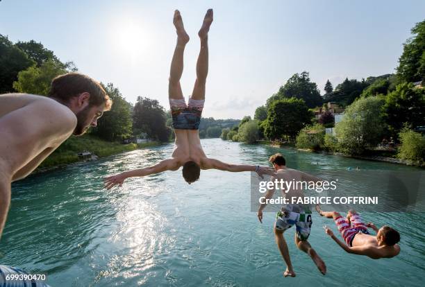 Young men jump into the river Aare on June 21, 2017 in Bern. - Europe sizzled in a continent-wide heatwave with London bracing for Britain's hottest...