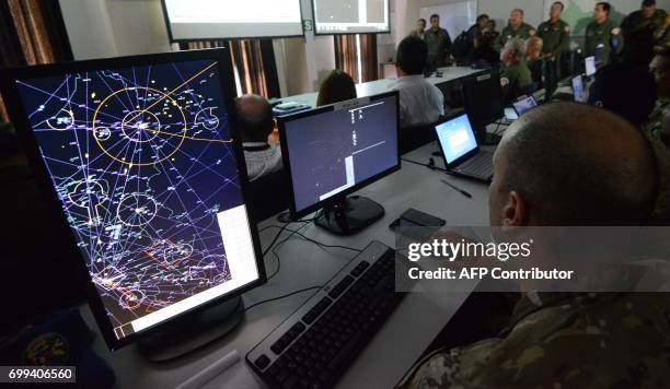 Members of a tri-national Air Force team of Brazil, Colombia and Peru watch from a control center the joint exercises designed to improve tactics and...