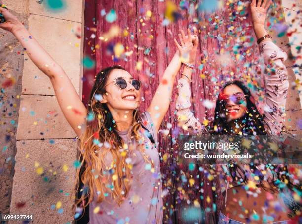 junge multi-ethnischen hipster frauen feiern mit konfetti in der stadt - celebration stock-fotos und bilder