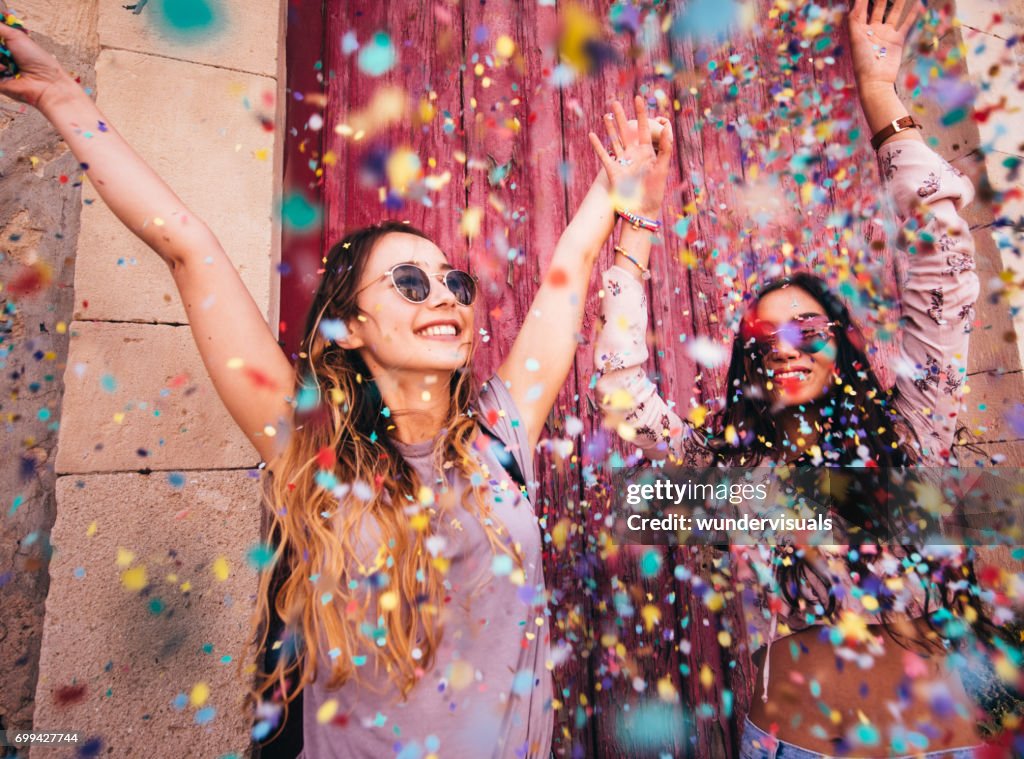 Mujeres jóvenes hipster multiétnica celebrando con confeti en la ciudad