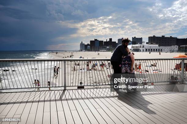 People relax along the boardwalk at Coney Island on the first day of summer on June 21, 2017 in New York City. Following an unseasonably wet spring,...