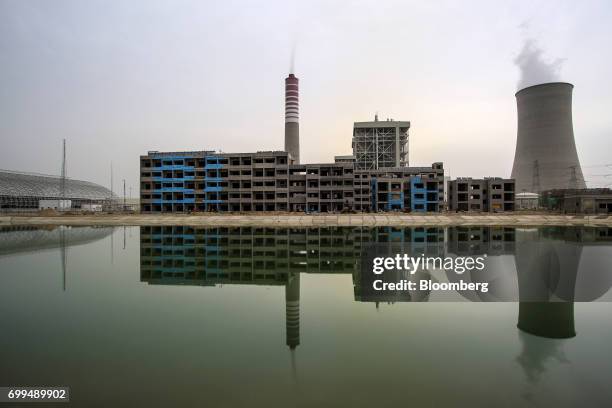 Vapor rises from a cooling tower behind a building under construction at the Sahiwal coal power plant, owned by China's state-owned Huaneng Shandong...