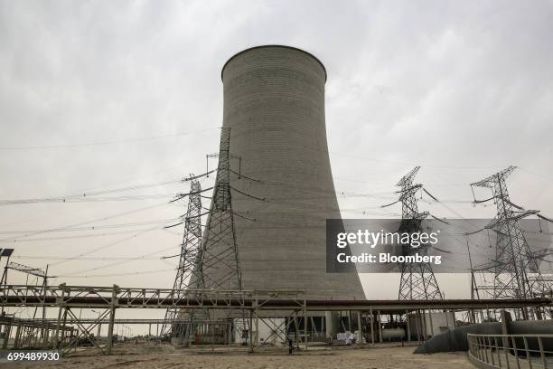 Power lines hang from transmission pylons in front of a cooling tower at the Sahiwal coal power plant, owned by China's state-owned Huaneng Shandong...