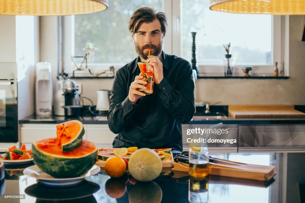 Handsome man drinking watermelon juice in the kitchen