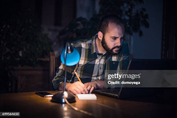 young man writing and using laptop at night - online library stock pictures, royalty-free photos & images