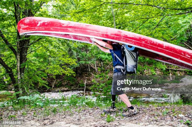 man with prosthetic leg carrying his canoe to the river - carrying canoe stock pictures, royalty-free photos & images