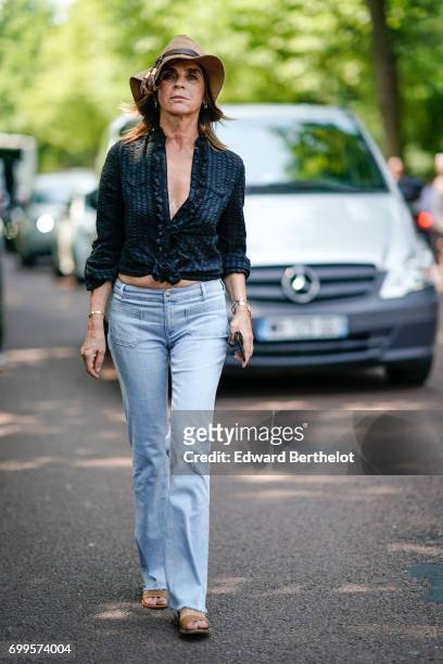Carine Roitfeld wears a camel hat, a black low neck shirt, blue denim jeans pants, outside the Balenciaga show, during Paris Fashion Week - Menswear...