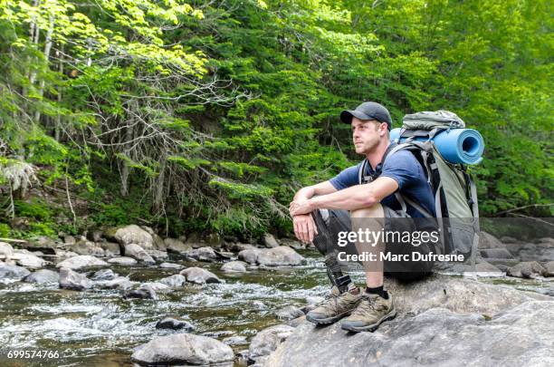 man with prosthetic leg sitting on rock by the river - fake man stock pictures, royalty-free photos & images