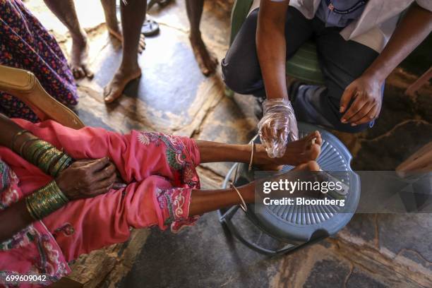 Member of the medical staff from the Jain Institute of Vascular Sciences examines the feet of a patient at a mobile clinic in Pancharala, on the...