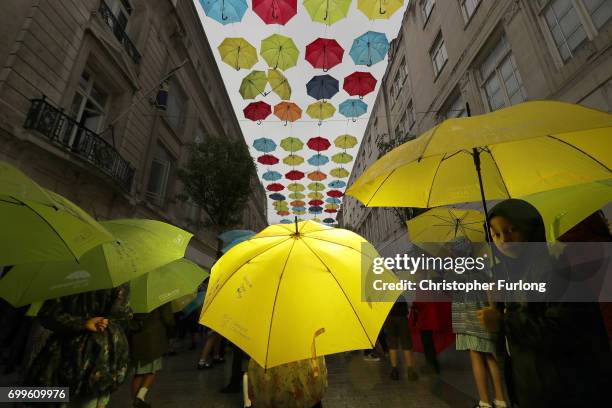 Young children dance with their umbrellas at the launch of an art installation called the Umbrella Project, featuring 200 brightly coloured umbrellas...