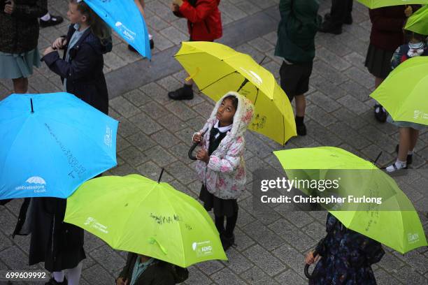 Young children dance with their umbrellas at the launch of an art installation called the Umbrella Project, featuring 200 brightly coloured umbrellas...