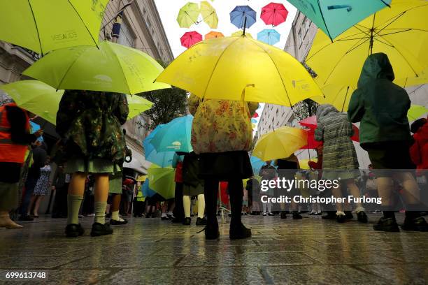 Young children dance with their umbrellas at the launch of an art installation called the Umbrella Project, featuring 200 brightly coloured umbrellas...