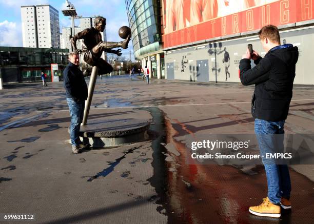 Fan has his photo taken with the Dennis Bergkamp statue outside the Emirates Stadium