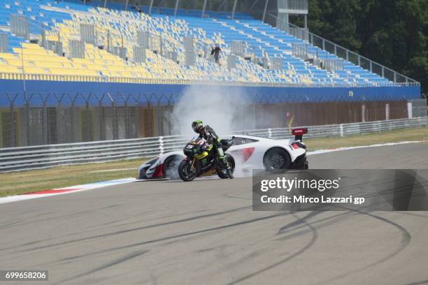 Johann Zarco of France and Monster Yamaha Tech 3 rides the bike and makes a burn out in front of Bruno Senna of Brazil drives the car during the...