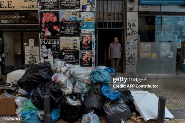 Man stands behind piles of garbage in central Athens on June 22, 2017 due to a strike of municipal workers. Contract municipal workers who face...