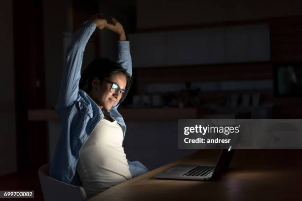 femme travaillant tard en ligne à la maison et qui s’étend - yawning stock photos et images de collection