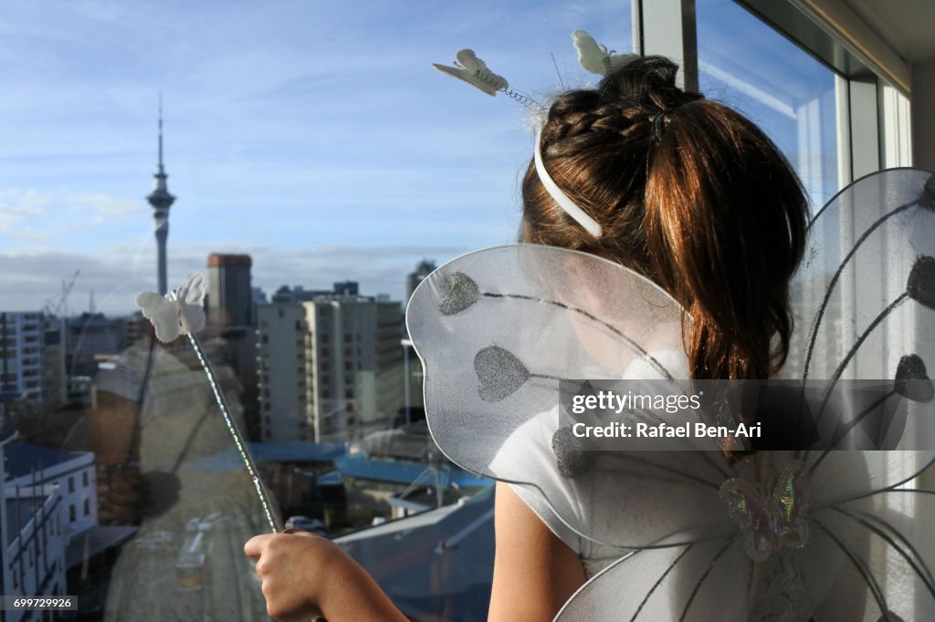 Girl looks out of a window overlooking a city landscape