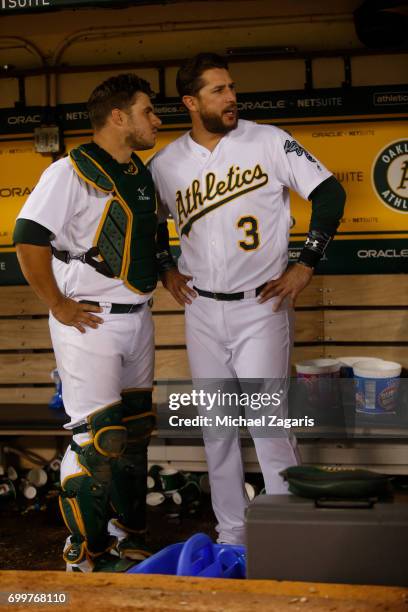 Josh Phegley and Trevor Plouffe of the Oakland Athletics talk in the dugout during the game against the Toronto Blue Jays at the Oakland Alameda...