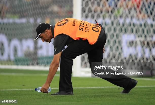 Stadium steward removes a bottle of water that was thrown onto the pitch.