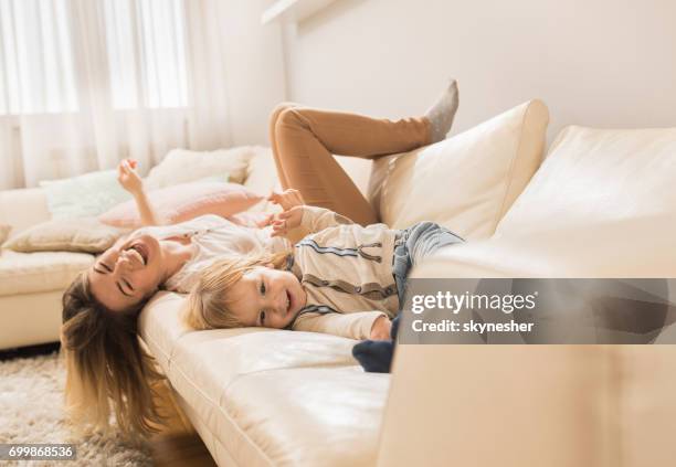 happy little boy and mother lying on the sofa and having fun together. - family on couch stock pictures, royalty-free photos & images